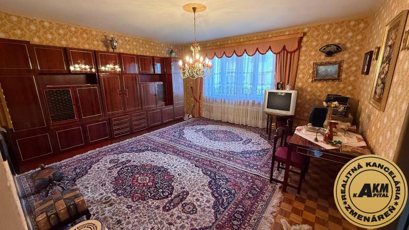 Wohnzimmer in einem Einfamilienhaus mit Teppich, älterem Fernseher und elegantem Kronleuchter.