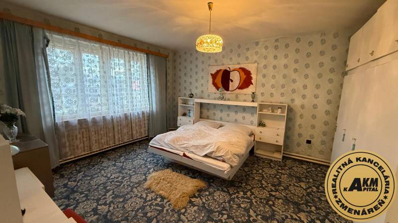 Ein Schlafzimmer in einem Einfamilienhaus mit einem Blumenmusterteppich und einem großen Fenster.