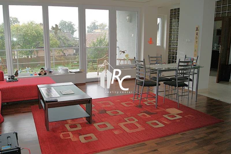 Wohnzimmer in einem Einfamilienhaus mit Holzboden und rotem Teppich.