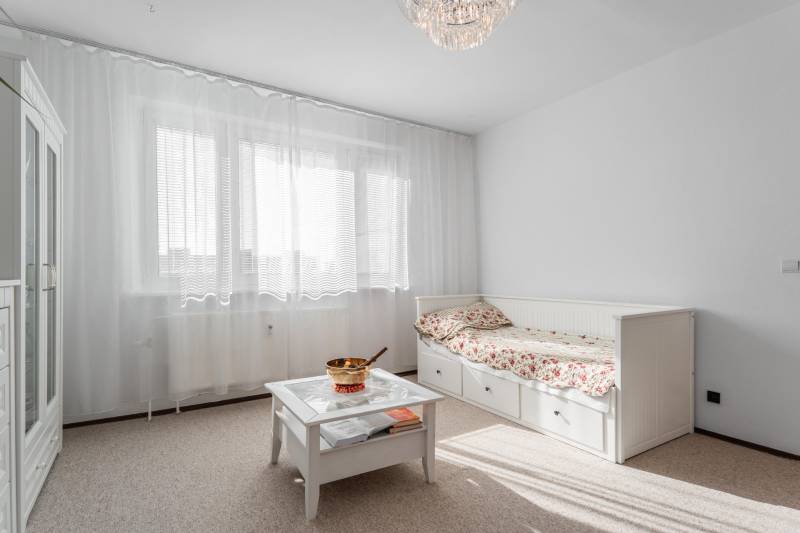 Helles Zimmer in einer 4-Zimmer-Wohnung mit Sofa, Tisch und Vorhängen am Fenster.