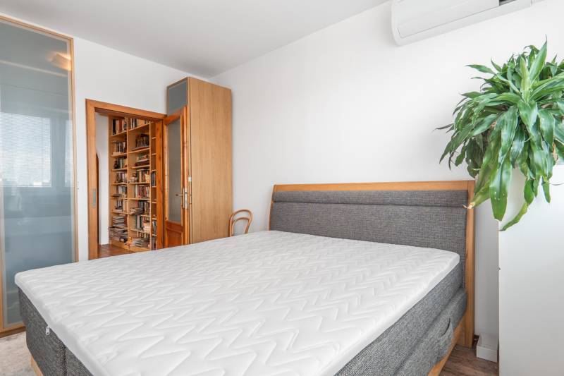 Schlafzimmer in einer 4-Zimmer-Wohnung mit Bett, Einbauschrank und Bücherregal.