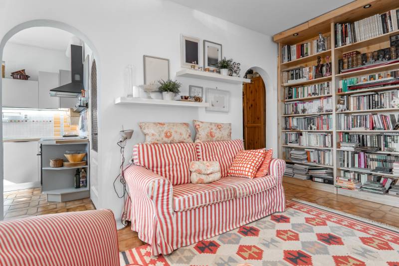 Wohnzimmer in einer 4-Zimmer-Wohnung mit gemustertem Sofa, Regal und Bücherregal.