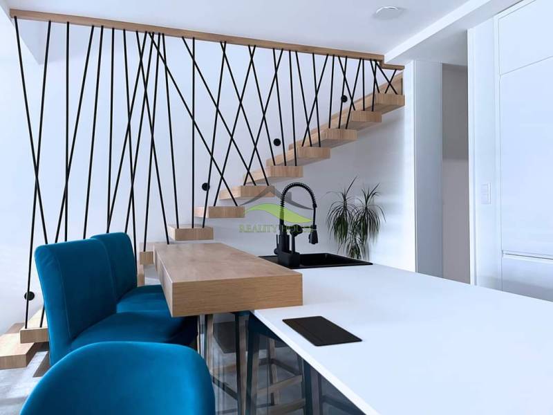 Innenraum eines Einfamilienhauses mit Treppe, blauen Stühlen und Küchentheke.