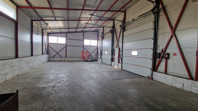 Ein geräumiger Raum mit hoher Decke und großen Toren in Skados und Hallen.