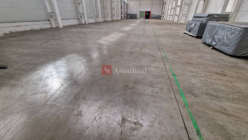 Geräumiges Inneres von Lagern und Hallen mit Betonboden und Paketen auf der linken Seite.