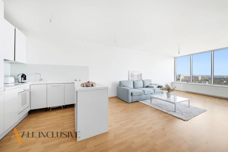 Gemütliche Küche mit weißen Schränken, einem Sofa und einer großen verglasten Wand in einer 2-Zimmer-Wohnung.