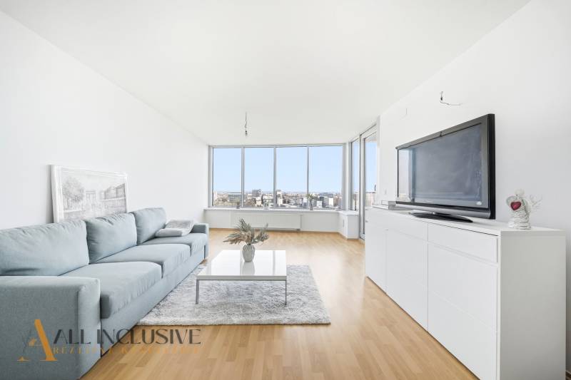 Wohnzimmer in einer Zweizimmerwohnung mit Sofa, Fernseher und Holzboden.