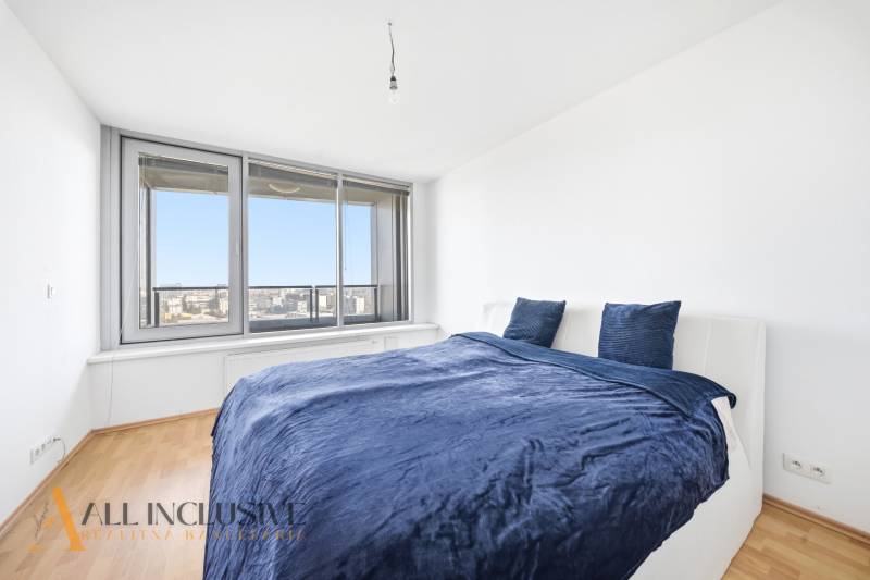 Schlafzimmer in einer 2-Zimmer-Wohnung mit Bett und großem Fenster, Boden mit Holzdekor.