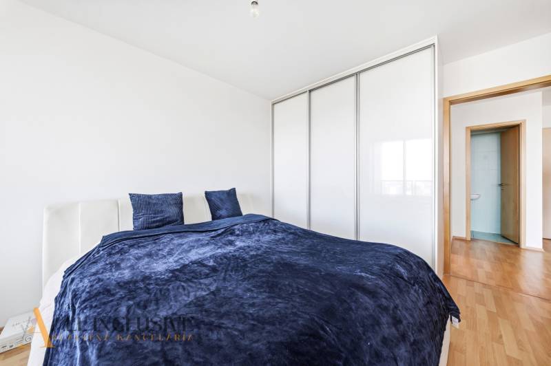 Schlafzimmer in einer 2-Zimmer-Wohnung mit Bett, Kleiderschrank und Boden in Holzoptik.