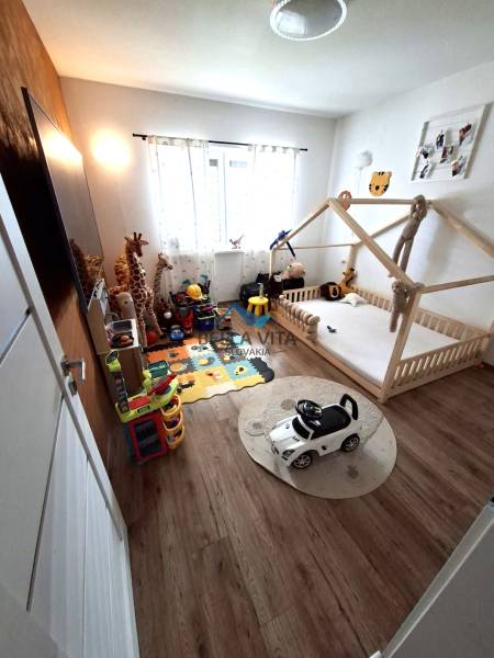 Kinderzimmer im Einfamilienhaus mit Kinderbett, Spielzeug und Boden in Holzoptik.