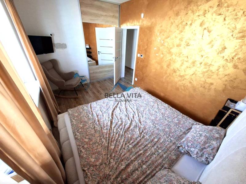 Ein Schlafzimmer in einem Einfamilienhaus mit Holzboden, braunen Vorhängen und einem gemusterten Bett.