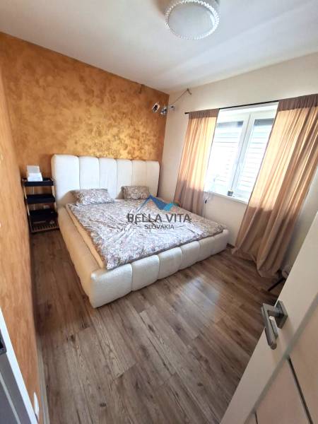 Ein Schlafzimmer in einem Einfamilienhaus mit einem Bett, einem Boden in Holzoptik und einer goldenen Wand.