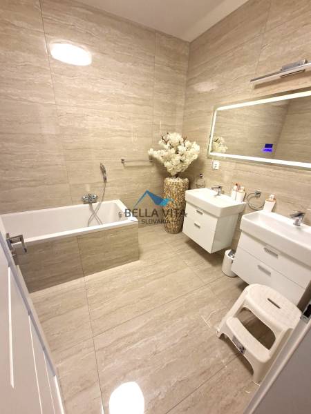 Ein Badezimmer im Einfamilienhaus mit Badewanne, Doppelwaschbecken und dekorativer Vase.