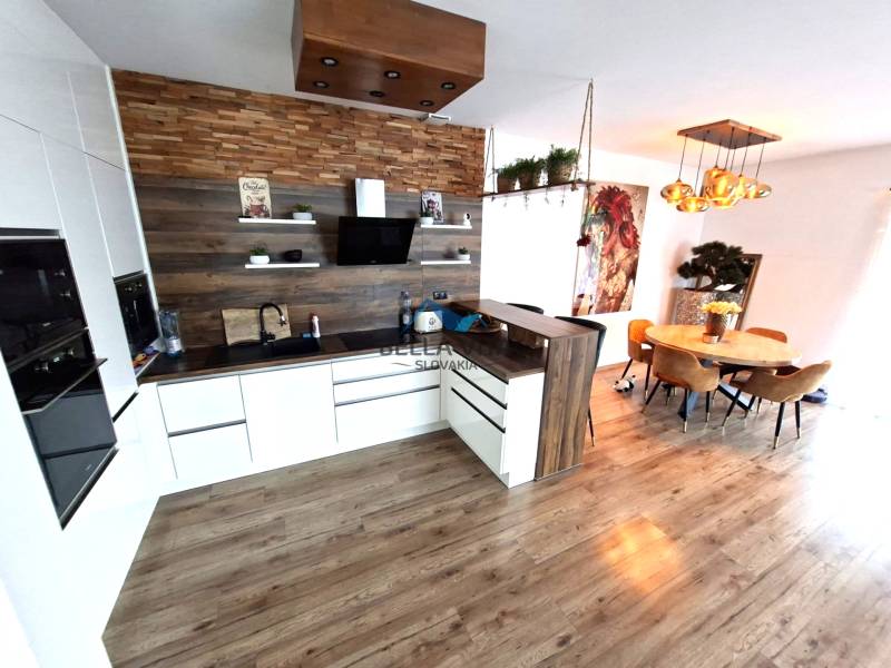 Eine Küche in einem Einfamilienhaus mit einem Holzboden, einem Esstisch und dekorativen Lichtern.