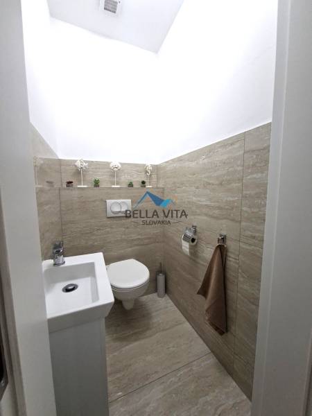 Kompakte Toilette in einem Einfamilienhaus mit Holzboden-Dekor, dekorative Details.