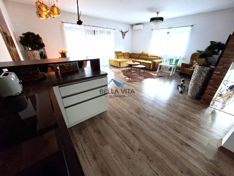 Wohnzimmer in einem Einfamilienhaus mit Holzboden und heller Couch.