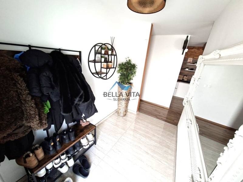 Innenraum eines Einfamilienhauses mit Kleiderhaken, Spiegel und Boden in Holzoptik.