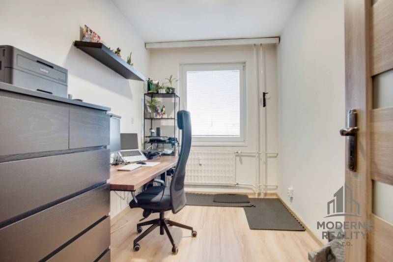 Heimbüro mit Tisch, Stuhl und Regal in einer 3-Zimmer-Wohnung mit Holzboden.
