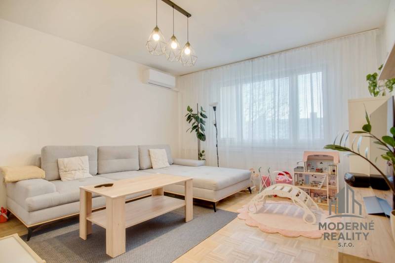 Helles Wohnzimmer mit Sofa, Kinderspielzeug und Holzboden in einer 3-Zimmer-Wohnung.