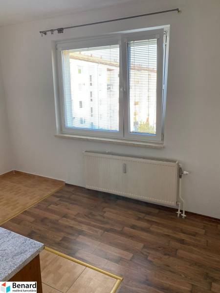 Weiße Wand, Fenster mit Jalousien, Boden mit Holzdekor, Heizkörper in einer 3-Zimmer-Wohnung.