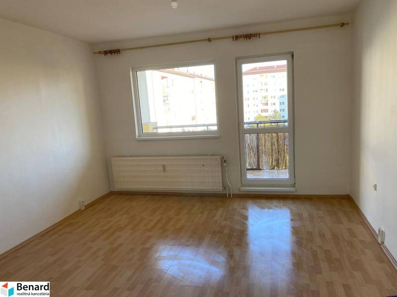 Ein Zimmer in einer 3-Zimmer-Wohnung mit Holzboden und Zugang zum Balkon.