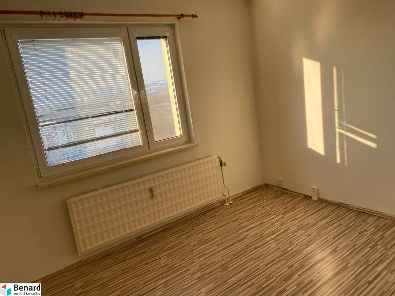 Ein Zimmer mit einem großen Fenster und einem Boden in Holzoptik in einer 3-Zimmer-Wohnung.