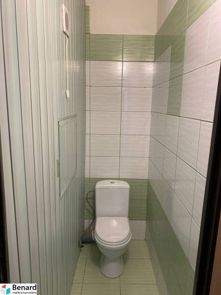 Toilette in einer 3-Zimmer-Wohnung mit Fliesen in grün-weißen Tönen.