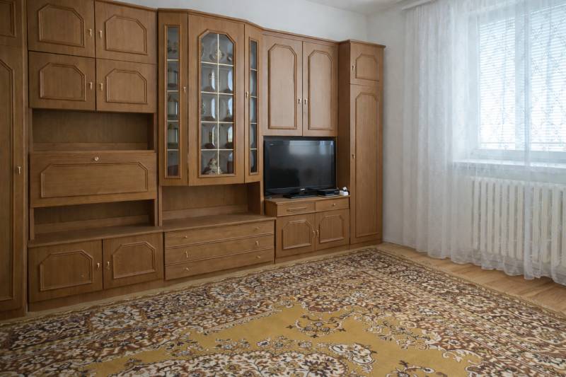 Wohnzimmer in einem Einfamilienhaus mit einer Wohnwand aus Holz und einem gemusterten Teppich.