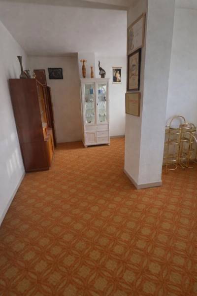 Innenraum eines Einfamilienhauses mit Vitrine und Teppichboden, Dekorationen und Bildern an den Wänden.