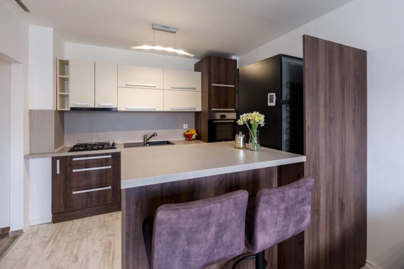 Küche in einer 2-Zimmer-Wohnung mit Bartresen, Tresen mit Holzboden-Dekor, Stühle.