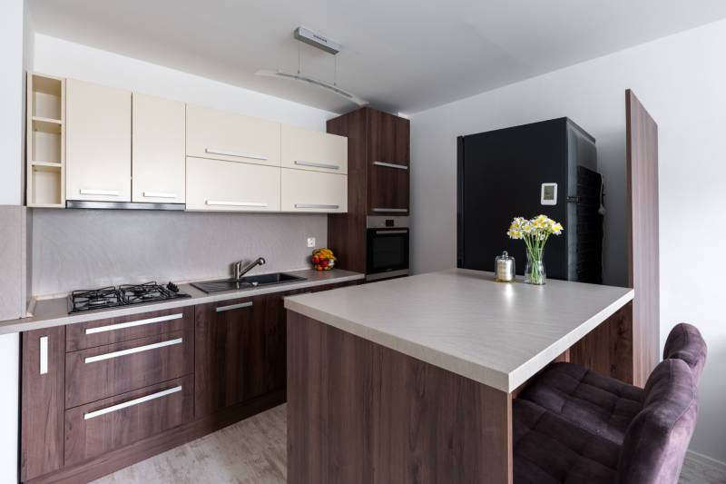 Küche in einer 2-Zimmer-Wohnung mit Holzboden, Bartresen und moderner Ausstattung.