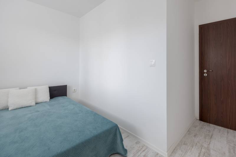 Schlafzimmer in einer 2-Zimmer-Wohnung mit Bett, Kissen und Holztüren.