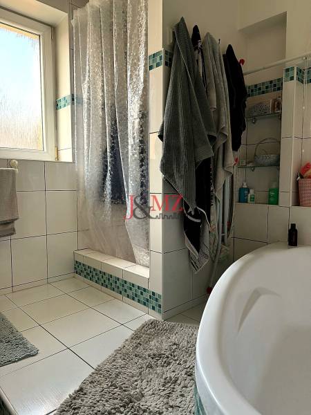 Badezimmer in einer 2-Zimmer-Wohnung mit Badewanne, Dusche und Fenster.