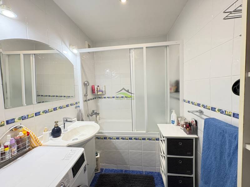 Badezimmer in einer 3-Zimmer-Wohnung mit Badewanne, Dusche und Waschmaschine, Fliesen mit Dekor.