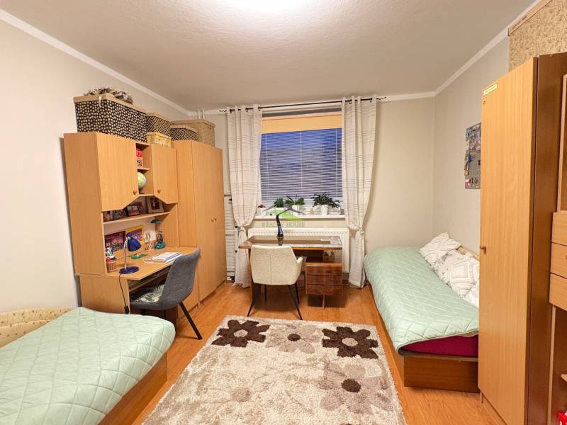 Ein Zimmer in einer 3-Zimmer-Wohnung mit einem Schreibtisch, einem Holzboden und zwei Betten.