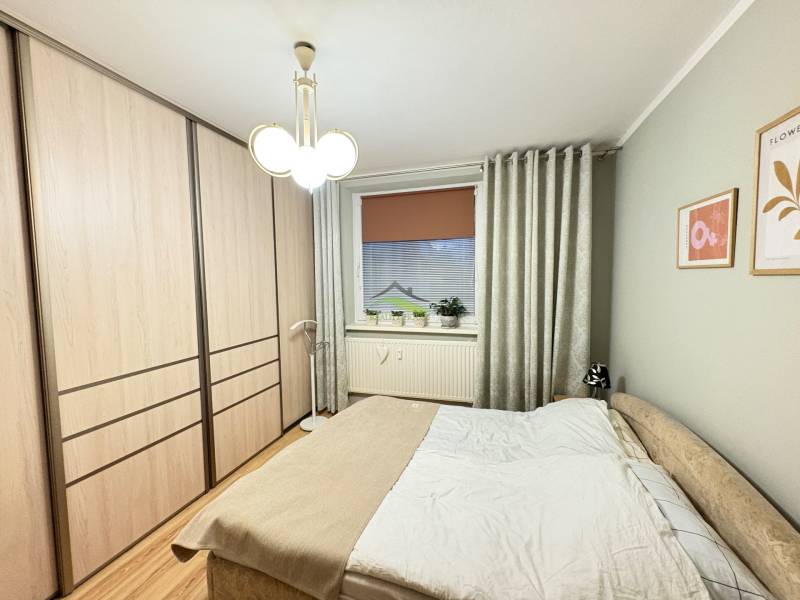 Schlafzimmer mit Bett, Einbauschrank und Boden mit Holzdekor in einer 3-Zimmer-Wohnung.