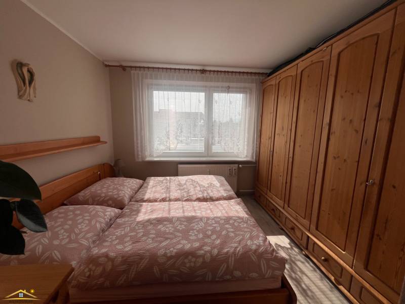 Schlafzimmer in einer 3-Zimmer-Wohnung mit einem großen Holzschrank und einem Bett.