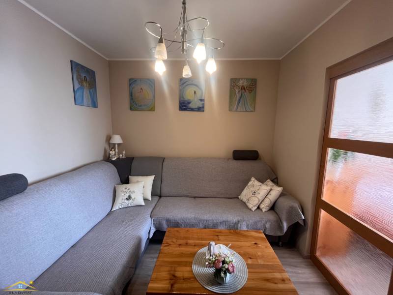 Wohnzimmer in einer 3-Zimmer-Wohnung mit Sofa, Bildern und Holzboden.