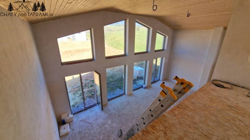 Das Innere der Hütte mit großen Fenstern, Treppenstufen und einem Boden mit Holzdekor.