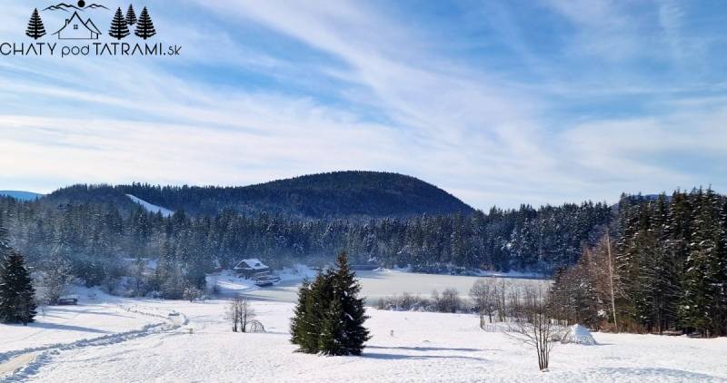 Verschneite Landschaft in Dolná Lehota mit einer Hütte und Wald im Hintergrund.