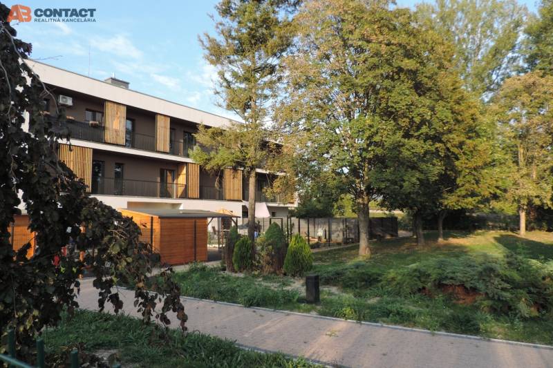 Das Wohnhaus in der Bodona-Straße, umgeben von Grünflächen und Bäumen, ideal für das Wohnen in einer Einzimmerwohnung.