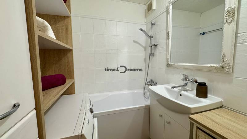 Badezimmer in einer 3-Zimmer-Wohnung mit Badewanne, Waschbecken und Regalspeicherplatz.