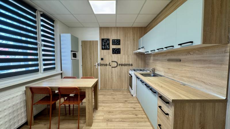 Küche in einer 3-Zimmer-Wohnung mit Esstisch und Boden mit Holzdekor.