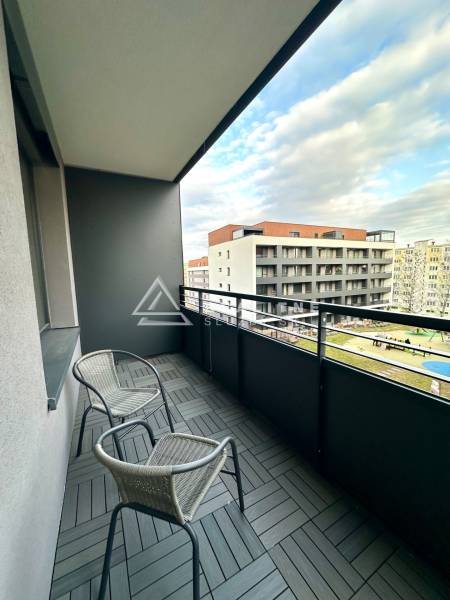 Ein Balkon mit zwei Stühlen und Fliesen in Holzoptik, Blick auf Gebäude.