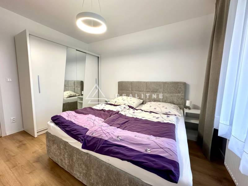 Schlafzimmer in einer Zweizimmerwohnung mit Holzboden, Schrank und Bett.