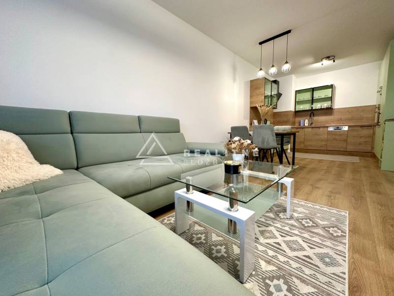 Wohnzimmer in einer 2-Zimmer-Wohnung mit Holzboden und bequemer Couch.