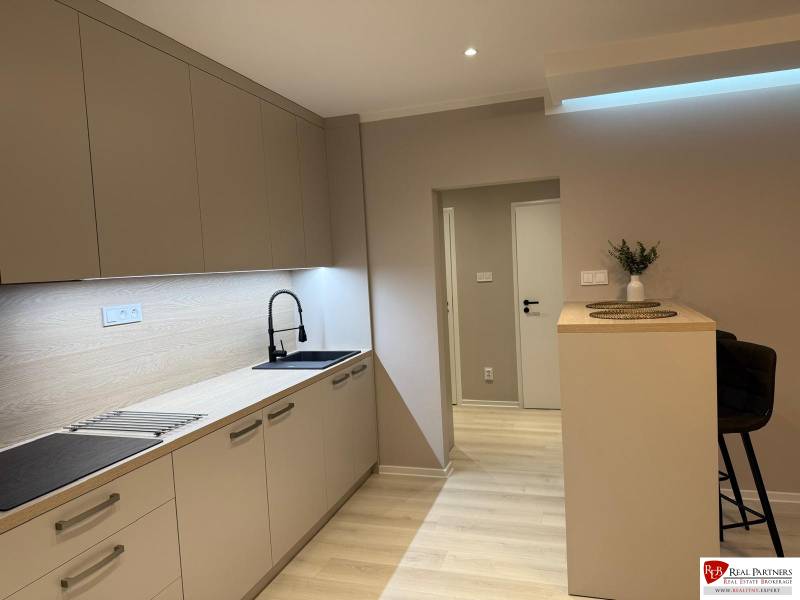 Küche in einer 2-Zimmer-Wohnung mit Holzboden und Küchenzeile.