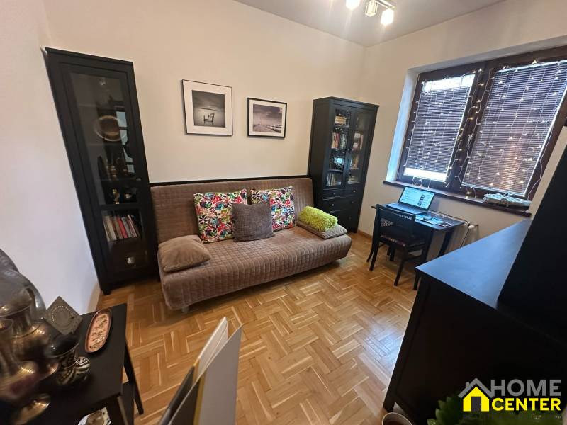 Wohnzimmer mit Sofa und Schreibtisch in einem Einfamilienhaus mit Holzboden.