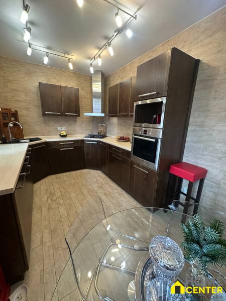 Küche in einem Einfamilienhaus mit Holzboden-Dekor und reichhaltiger Beleuchtung.