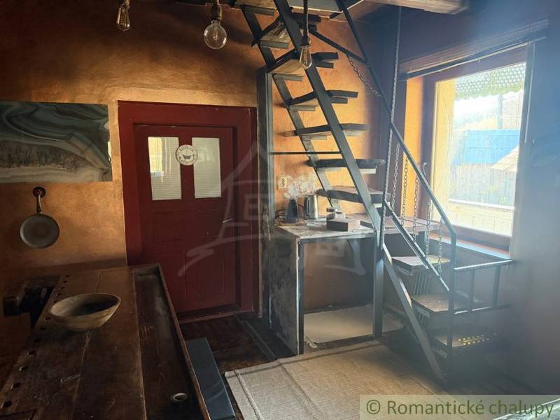 Innenraum eines Einfamilienhauses mit Metalltreppe und Holztisch, helle Wände.